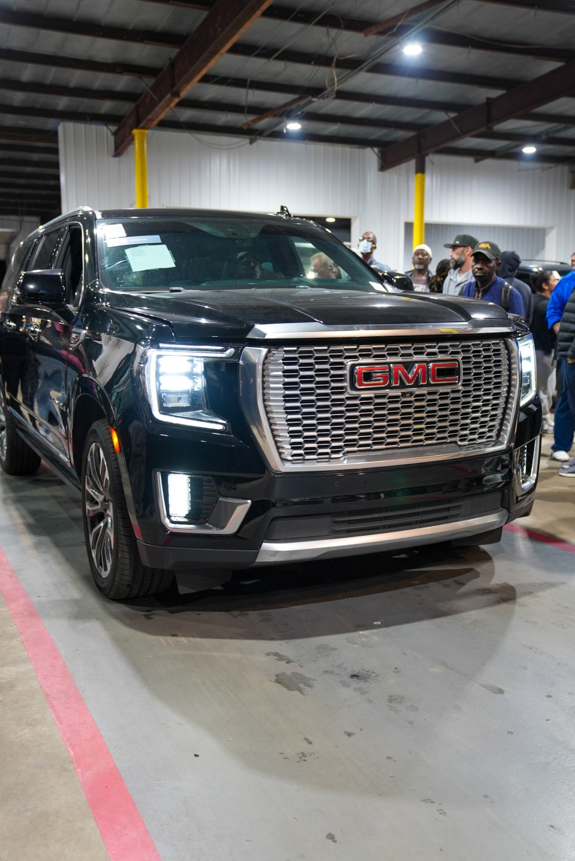 A black GMC SUV moving through a live Delaware Auto Exchange auction lane